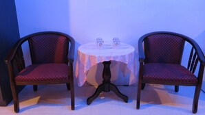 Dos sillones tapizados con tela estampada, una mesita redonda con mantel de encaje y dos candelabros de vidrio.