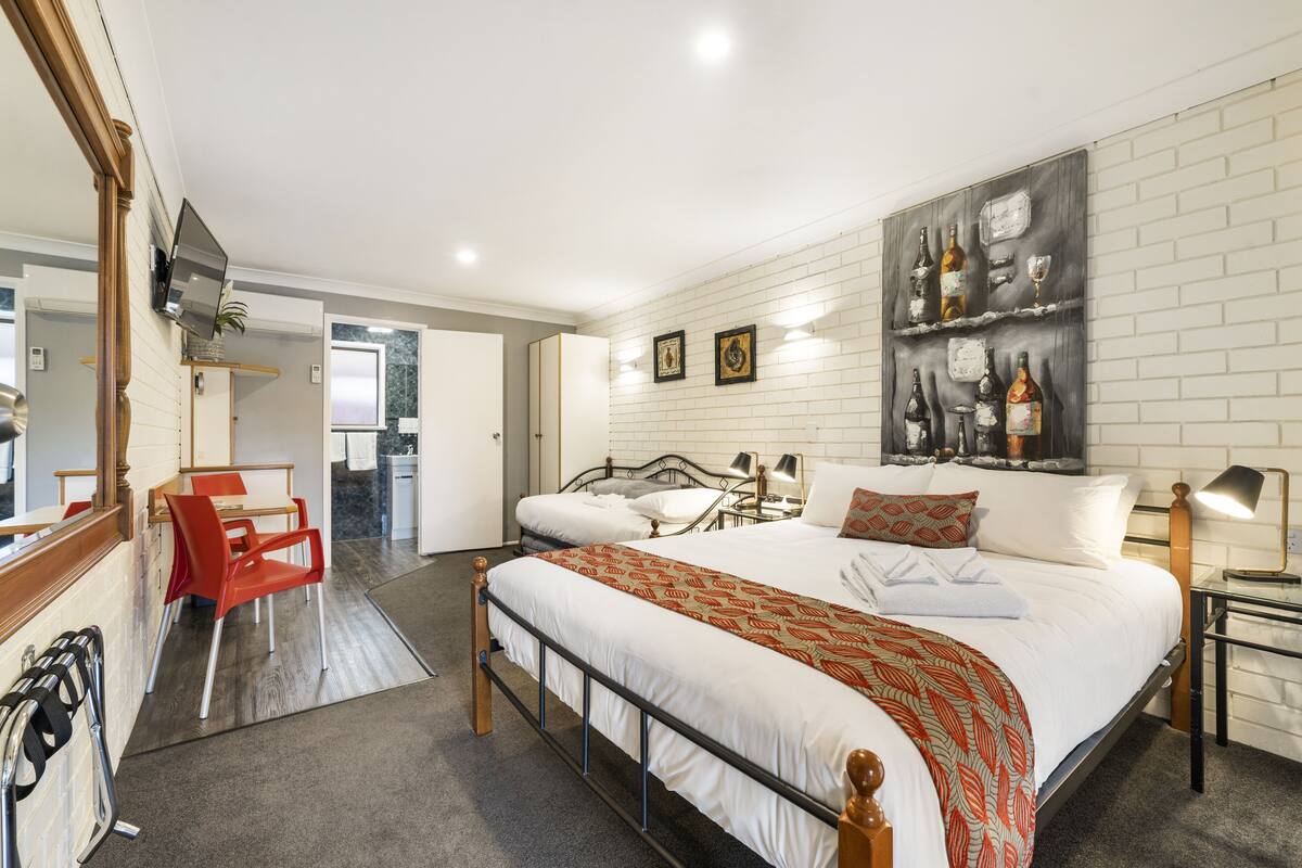 Une chambre d’hôtel avec un grand lit, un bureau avec une chaise, un miroir et un téléviseur fixé au mur.