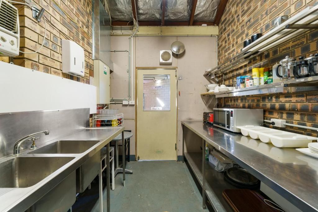 A kitchen with stainless steel countertops, a sink, and a door leading to another room.