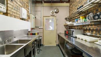 A kitchen with stainless steel countertops, a sink, and a door leading to another room.