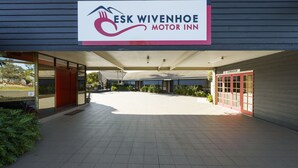 Entrada do Esk Wivenhoe Motor Inn, com uma placa acima da entrada, uma galeria coberta e o letreiro de uma academia visível à direita.