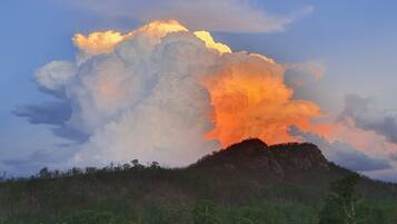 A landscape with a large cloud formation and a hill in the background.