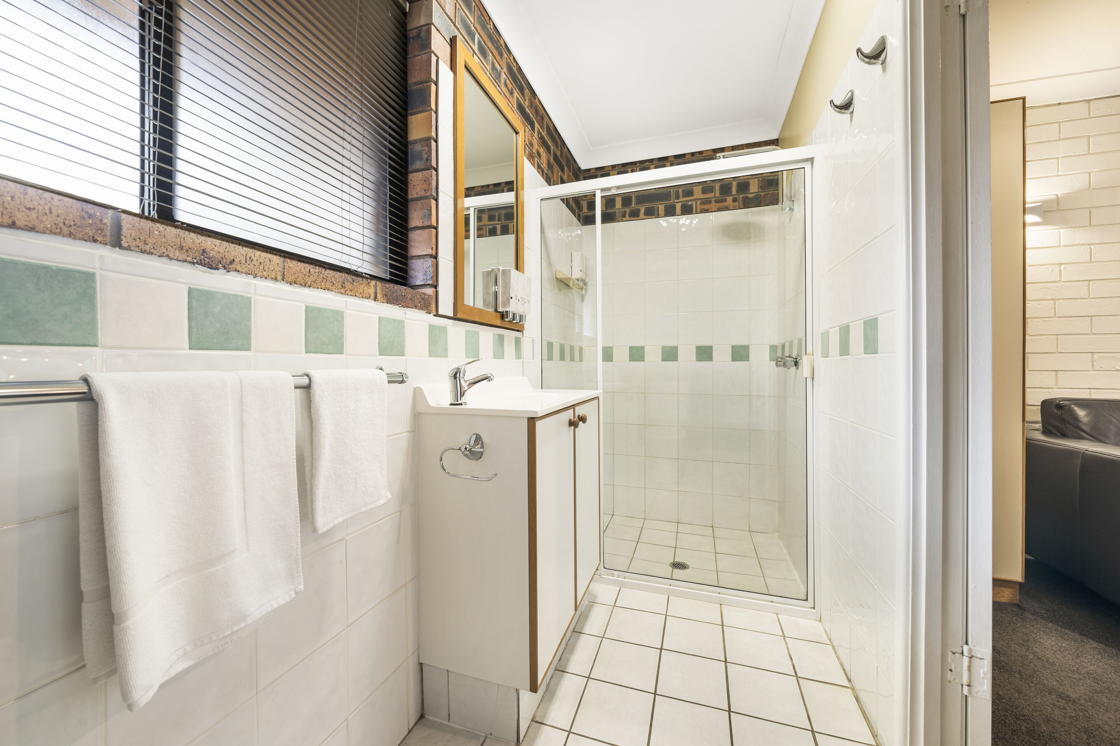 Une salle de bain avec une douche à parois de verre, un lavabo et un miroir.