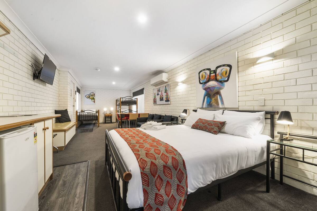 Une chambre d’hôtel comprenant un lit, une table de chevet, un bureau, une chaise et une petite kitchenette.