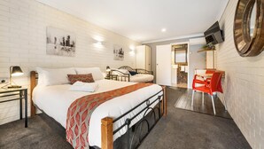 Quarto de hotel com uma cama grande, uma mesa com cadeira e um espelho na parede.