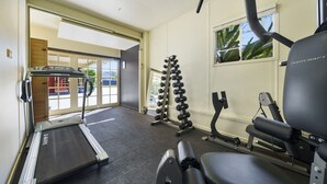 Uma academia com esteira, halteres e equipamentos de ginástica.