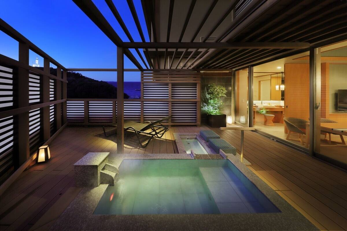 Una terraza moderna al aire libre con un jacuzzi, asientos y vistas al mar.