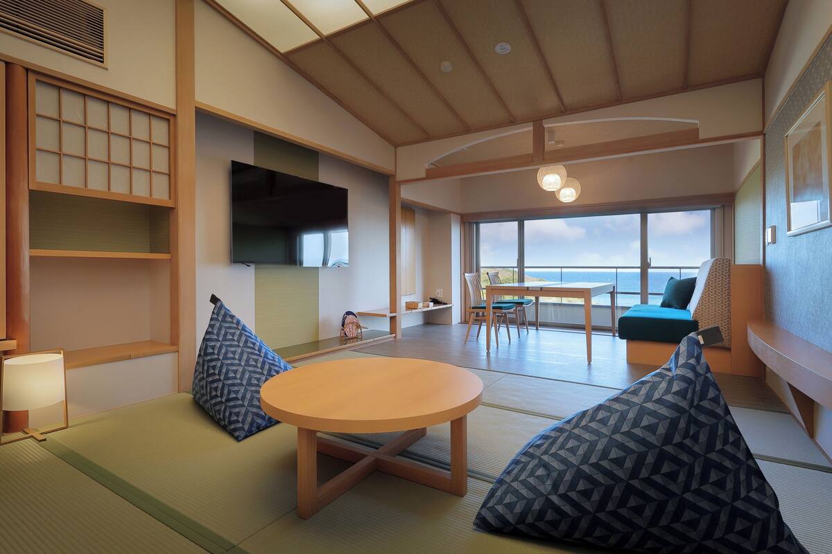 Una habitación tradicional japonesa con suelo de tatami, una mesa de madera baja y cojines.