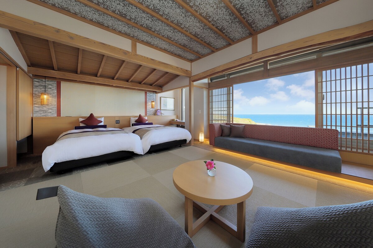 Une chambre d’hôtel avec un grand lit, un canapé, une petite table et une vue sur la mer.