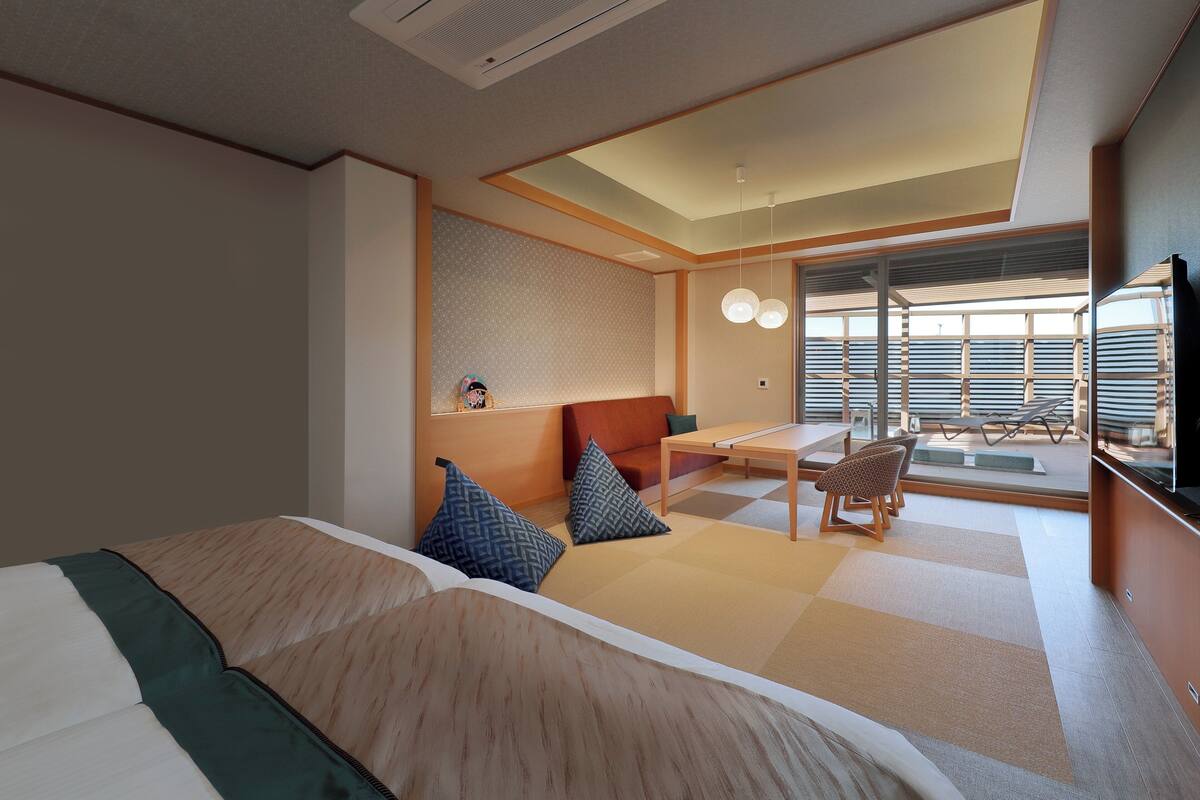 Habitación de hotel con cama, escritorio, silla y vistas al exterior.