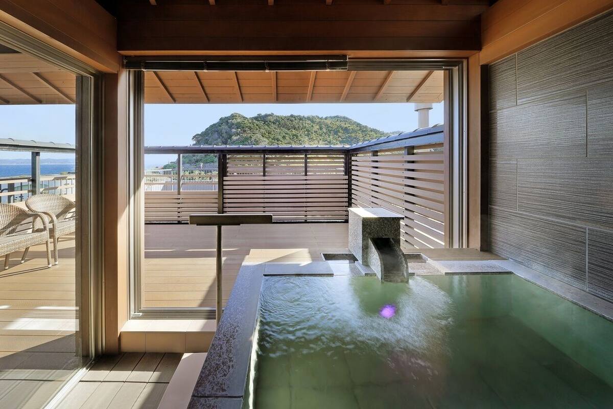 Un área de spa con jacuzzi, terraza de madera y vistas a un paisaje montañoso.