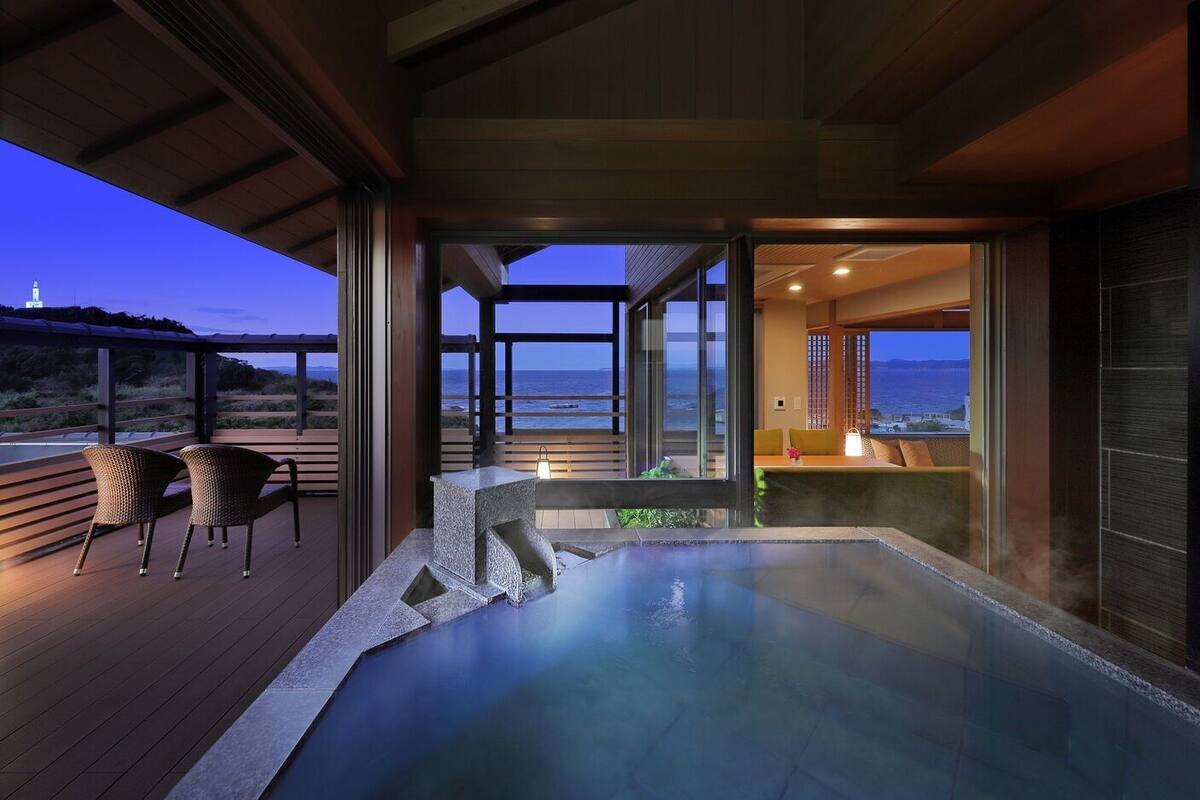 Un jacuzzi en una terraza con sillas, con vista a un cuerpo de agua.