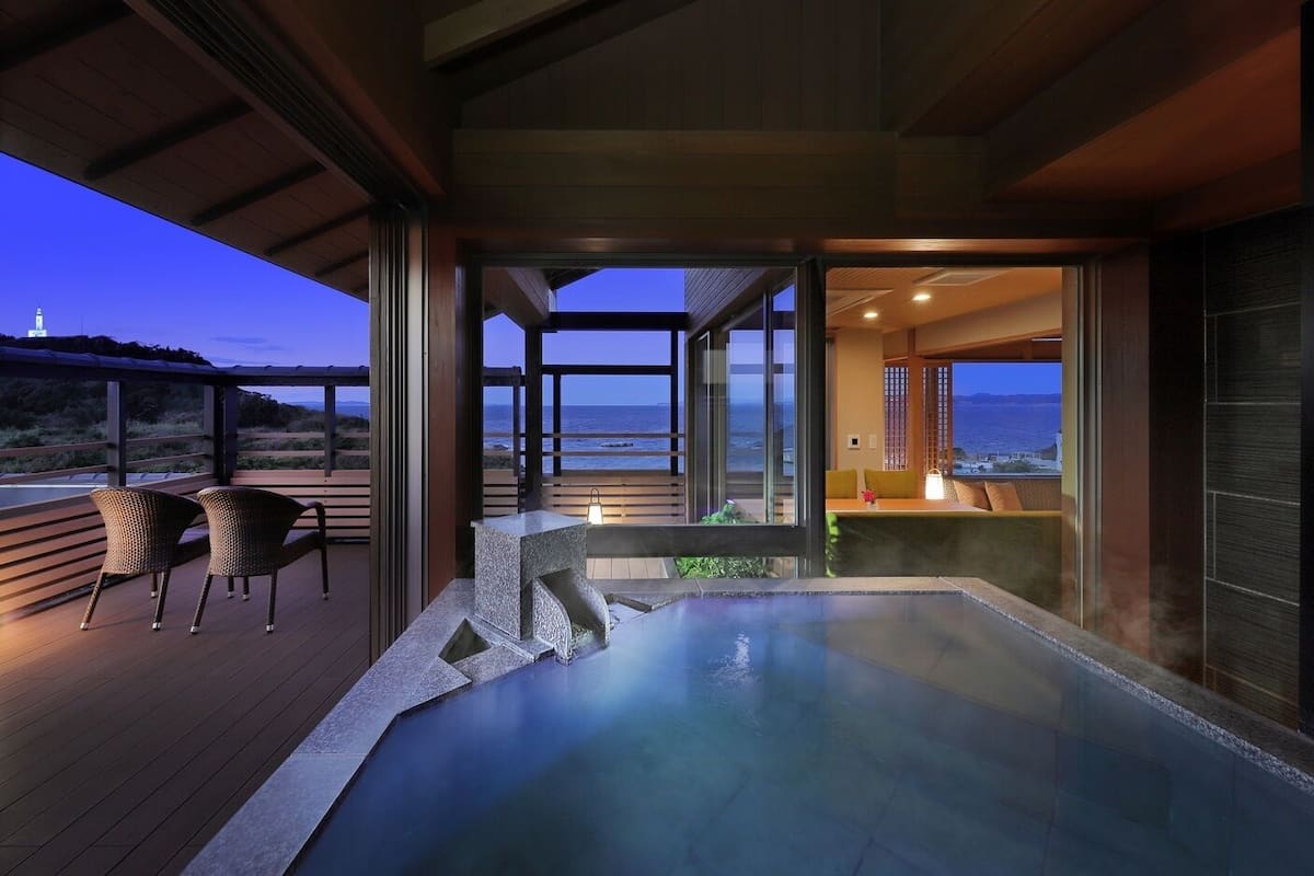 Un jacuzzi en una terraza con sillas, con vista a un cuerpo de agua.