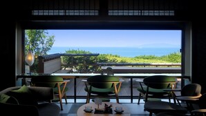 A room with a view of the sea, a table, chairs, and a window. - Hotel Sunosaki Kazenosho (Tateyama)