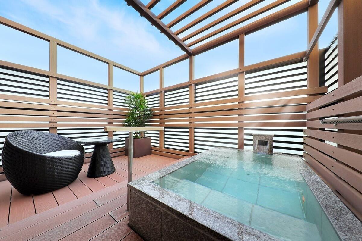 Terraza en la azotea con jacuzzi, zona de estar y una planta en maceta.