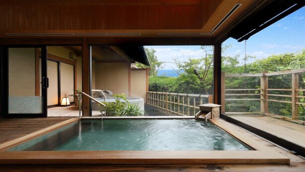 A hot spring bath with a wooden deck and a view of greenery. - Hotel Sunosaki Kazenosho (Tateyama)
