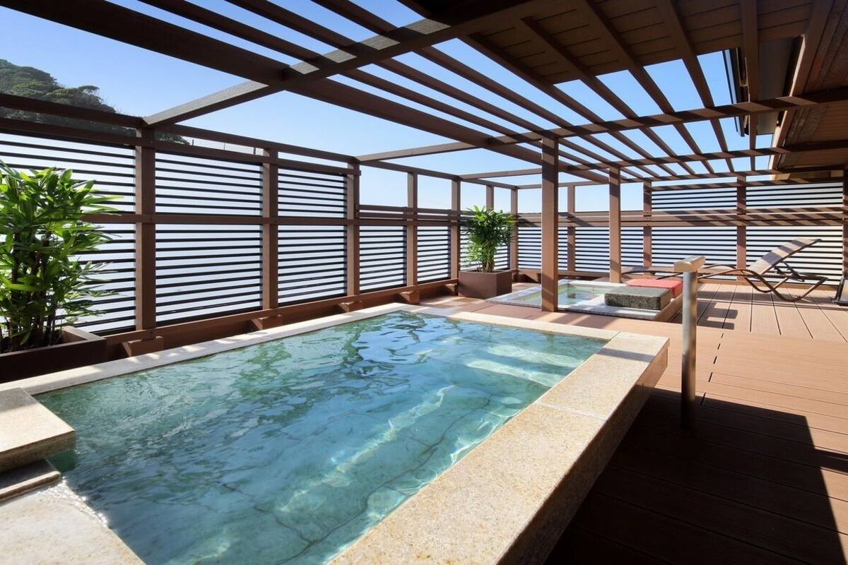 Zona de piscina en la azotea con vistas despejadas al cielo, terraza de madera y sillones de descanso.