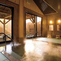 A hot spring area with a wooden interior, a glass door leading outside, and a small wooden bench.