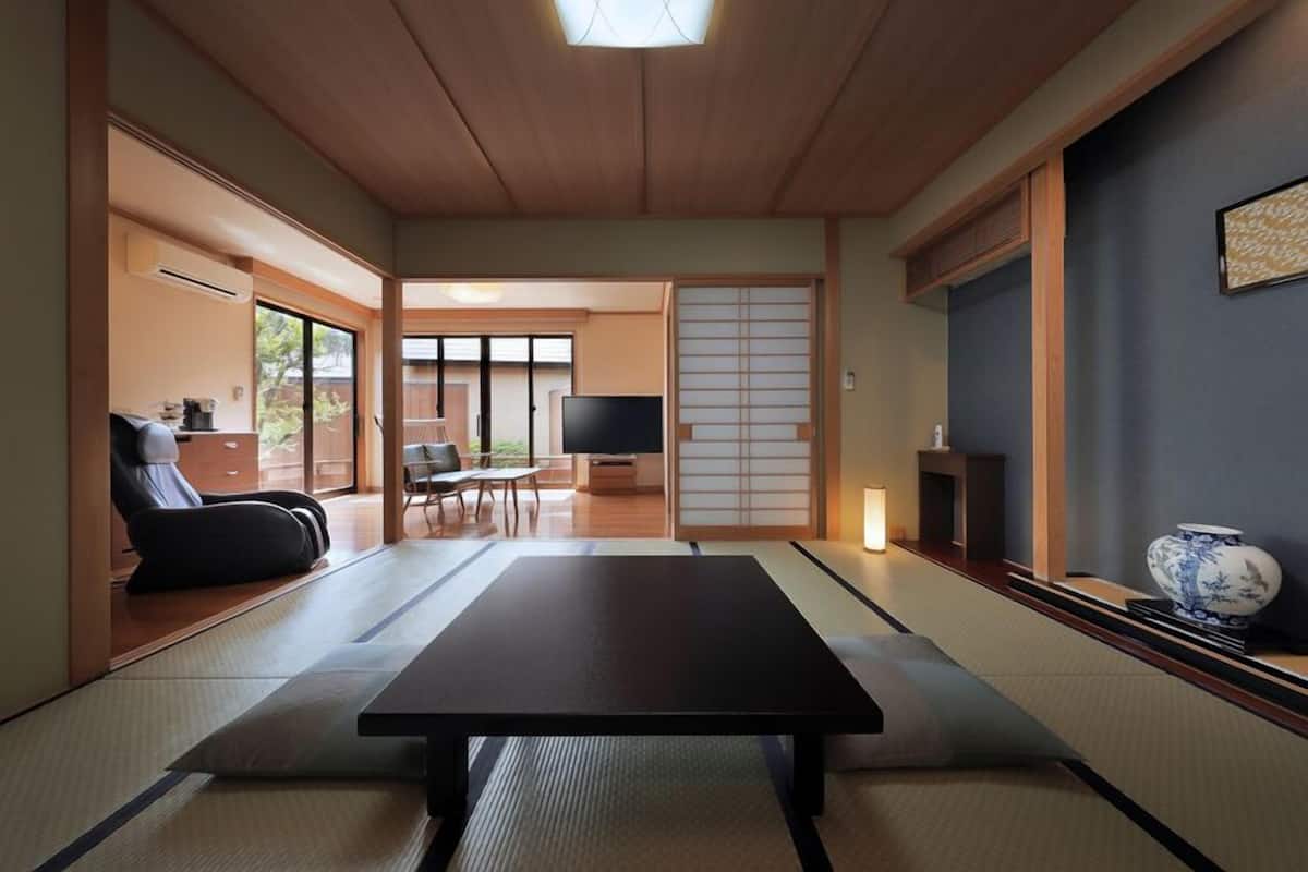 A traditional Japanese room with tatami flooring, a low table, a television, and sliding doors.
