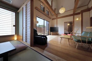 A traditional Japanese-style living room with tatami flooring, a low table, a sofa, and a television. - Shunsai no Yado Seasonal Inn Ryokusuitei (Kamogawa)