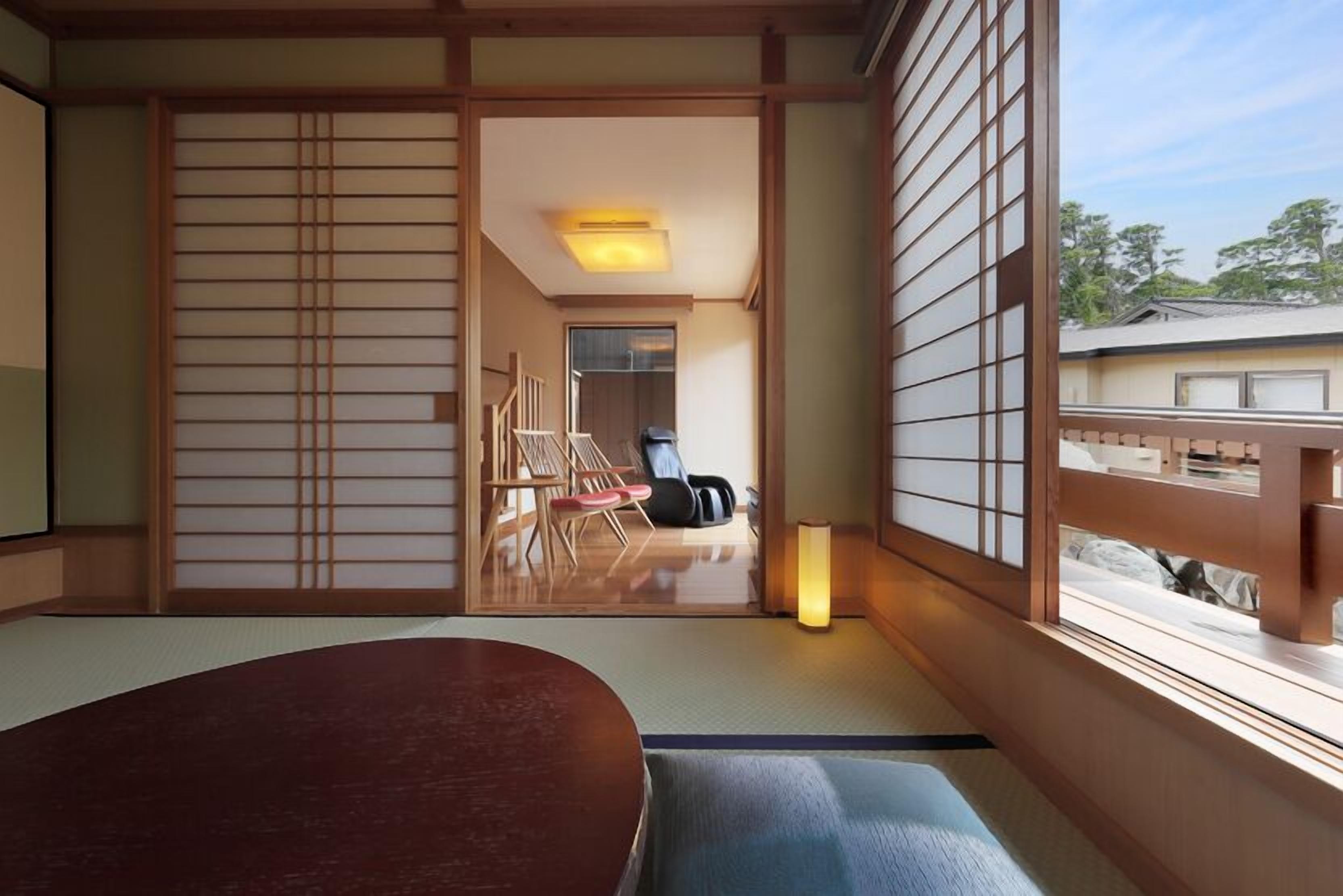 Une pièce de style japonais traditionnel, avec un sol recouvert de tatamis, une table basse, des portes coulissantes et une vue sur l’extérieur.