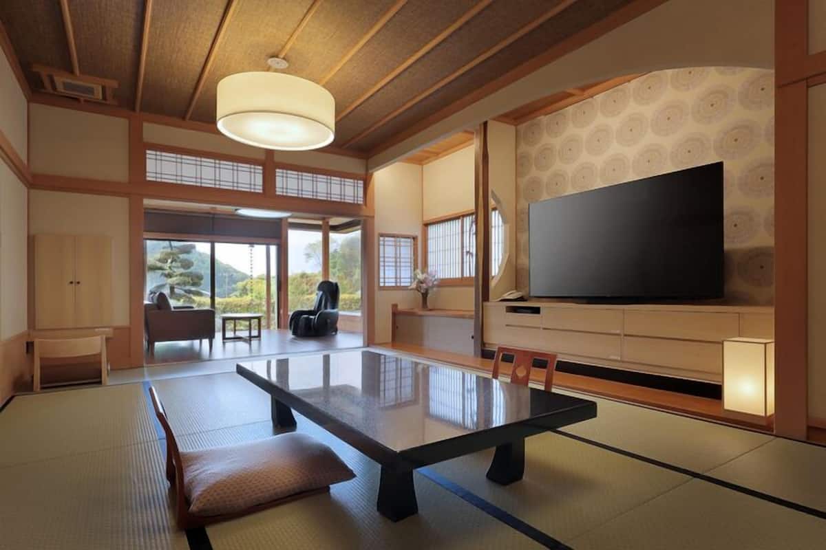 A traditional Japanese room with tatami flooring, a low table, a sofa, and a TV.