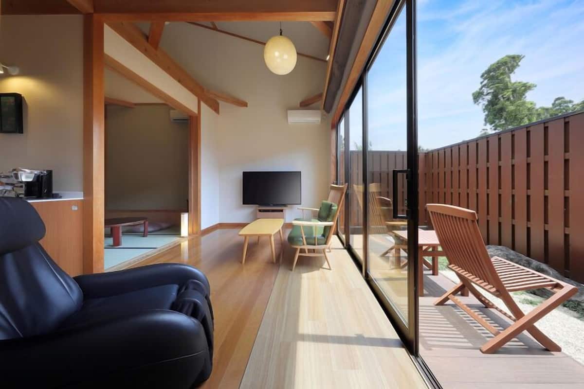 A modern living room with a TV, wooden furniture, and a large glass window.