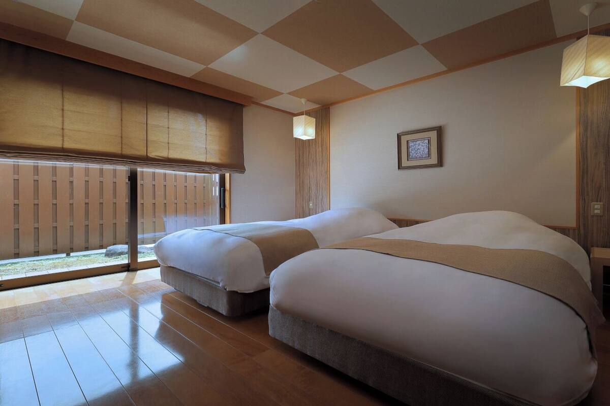 A hotel room with two beds, a large window with a view, and a traditional Japanese sliding door.