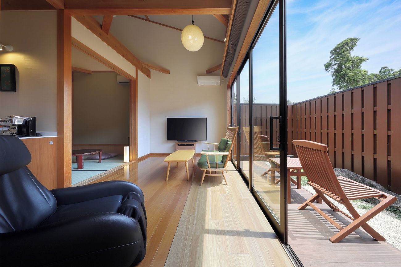 A modern interior with a flat-screen TV, wooden furniture, and a large window overlooking a deck.