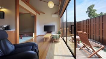 A modern interior with a flat-screen TV, wooden furniture, and a large window overlooking a deck.
