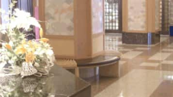 A lobby area with a reception desk, a vase of flowers, and a check-in counter.