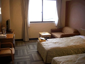 Una habitación de hotel con una cama, un escritorio, una silla y una mesita.