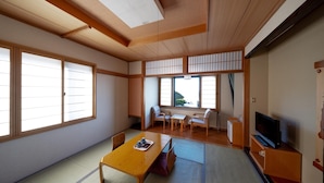 A traditional Japanese-style room with tatami flooring, a low wooden table, a television, and sliding shoji doors. - Mitsui Kanko Hotel (Rebun)