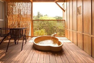 Una terraza de madera con un jacuzzi, una silla y una separador de bambú.