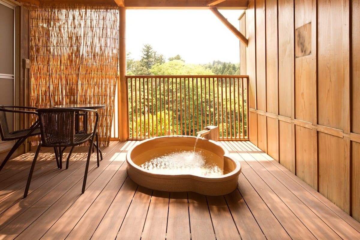 A wooden deck with a hot tub, a chair, and a bamboo screen.