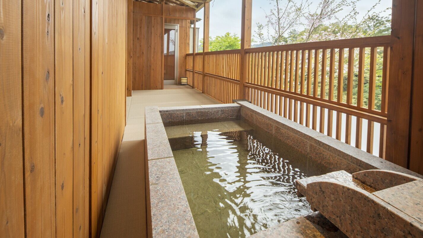 A wooden corridor with a stone hot spring bath.