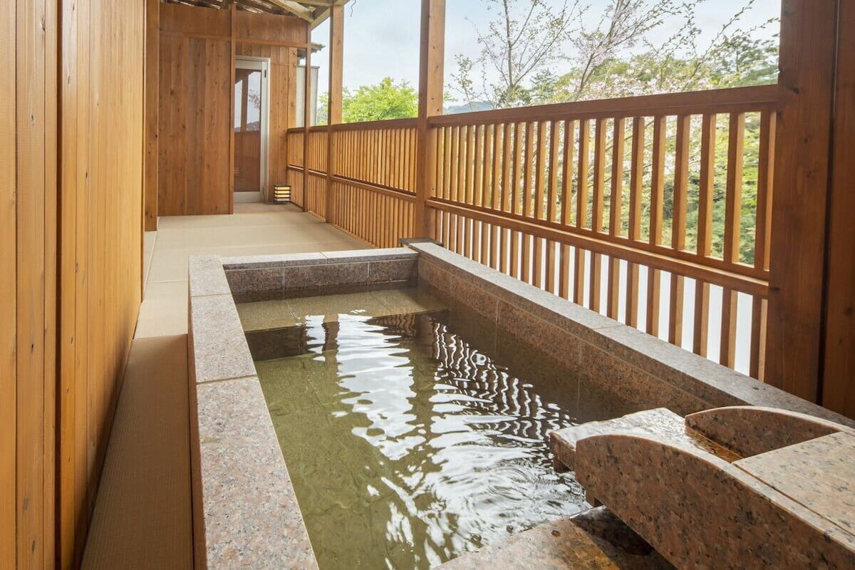 A wooden corridor with a stone hot spring bath.