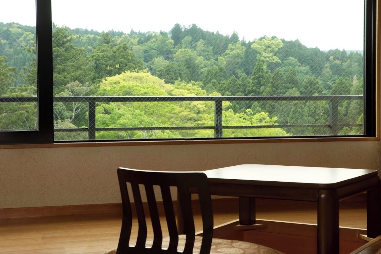 A room with a large window, a wooden chair, and a table.