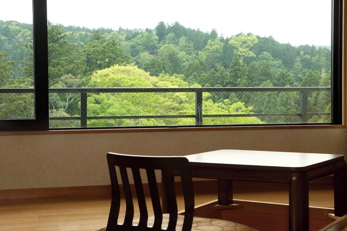 A room with a large window, a wooden chair, and a table.