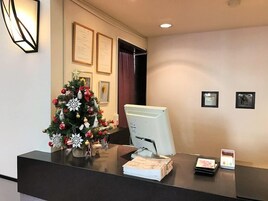 Una recepción con una computadora, un pequeño árbol de Navidad y certificados enmarcados en la pared.