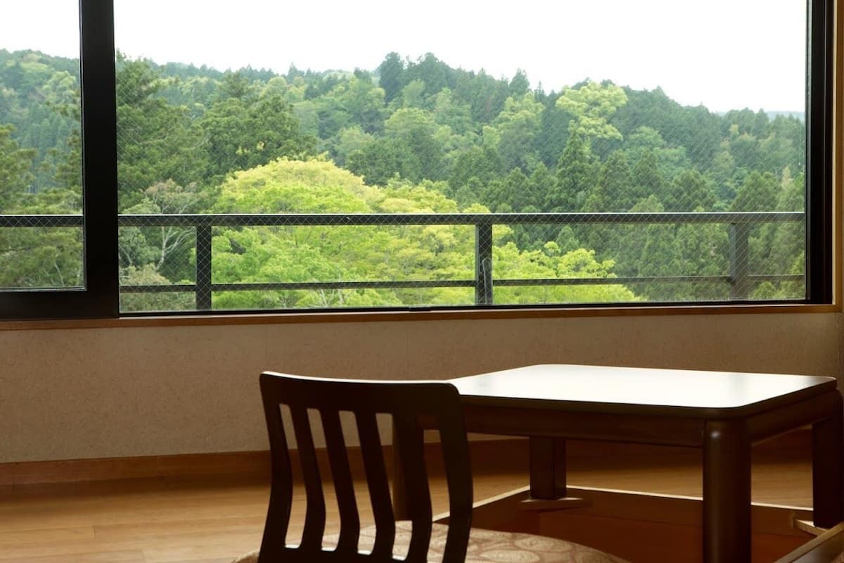 A room with a large window, a wooden chair, and a table.