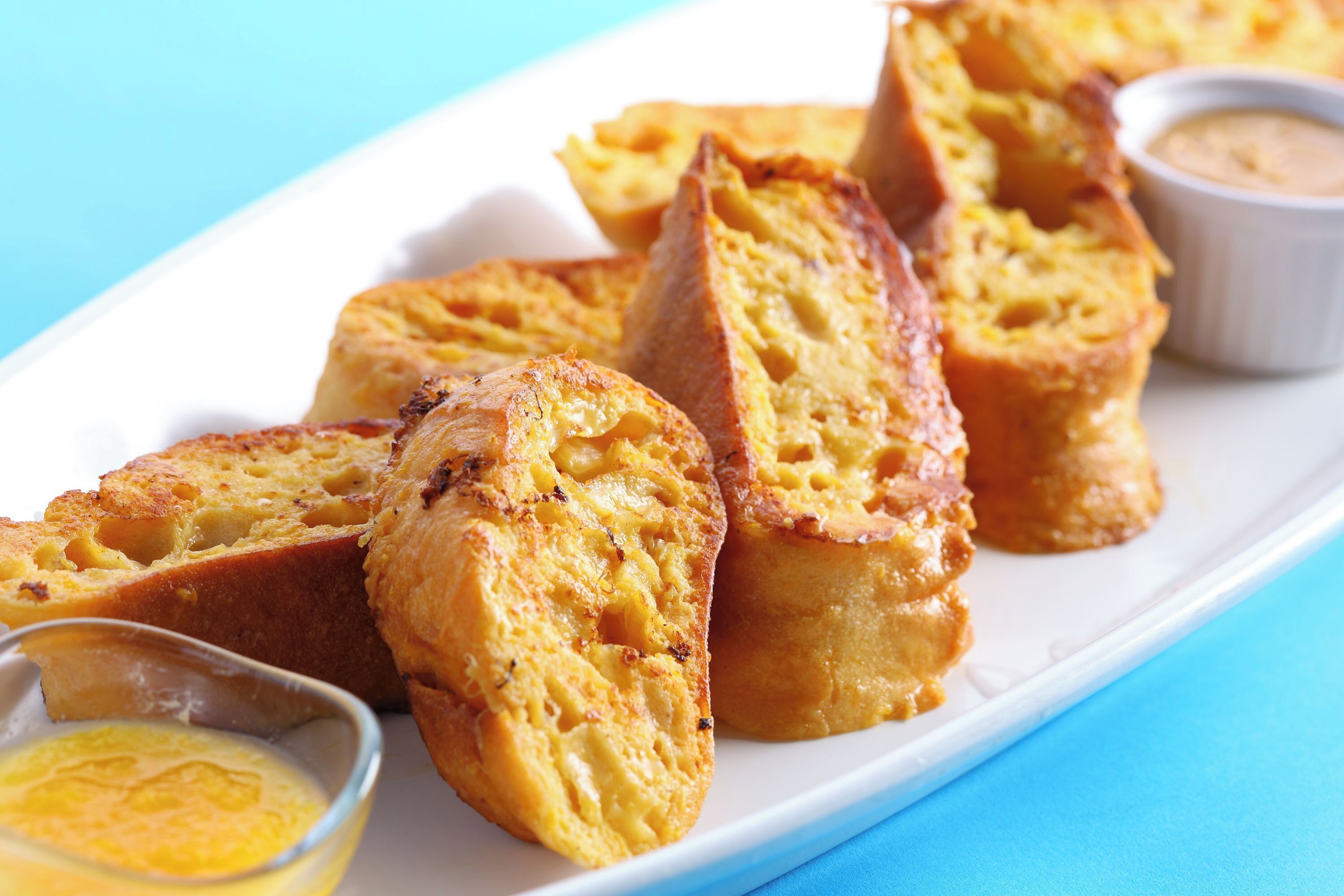A plate of toasted bread with butter and a small bowl of sauce.
