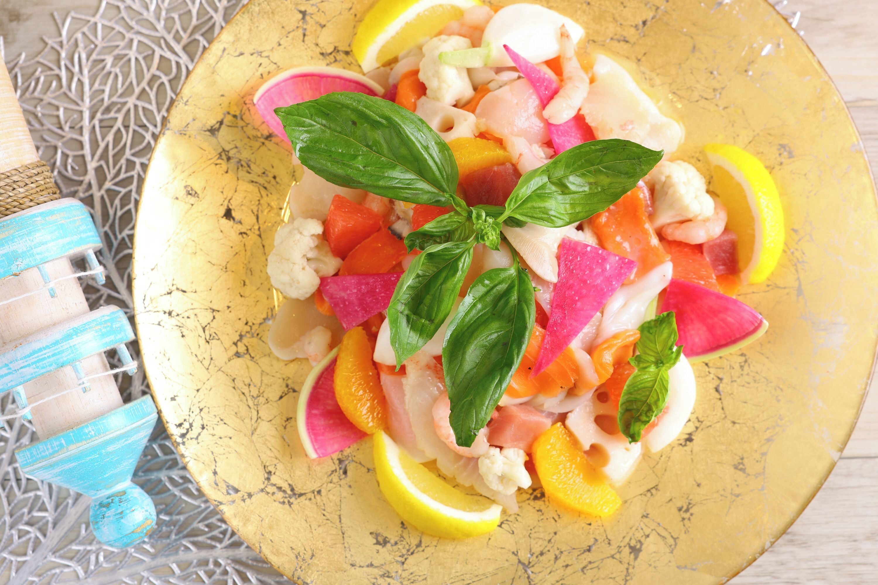 A plate of colorful fruit salad with basil leaves on a yellow plate.
