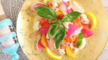 A plate of colorful fruit salad with basil leaves on a yellow plate.
