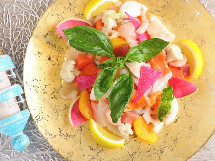 A plate of colorful fruit salad with basil leaves on a yellow plate.