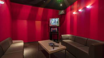 A red-walled room with a television, a table, and two sofas.