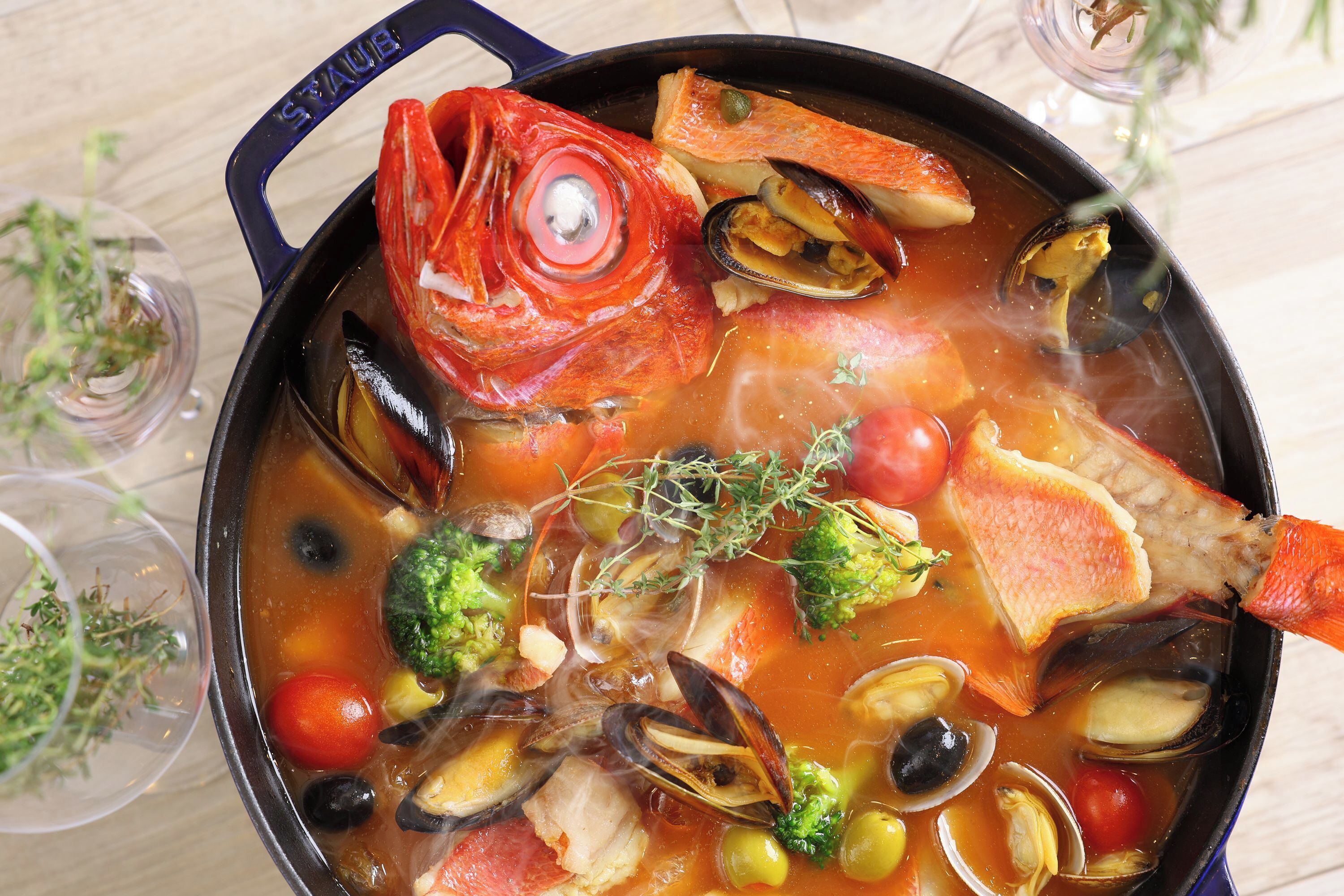 A pot of seafood stew with various ingredients like fish, mussels, and vegetables.