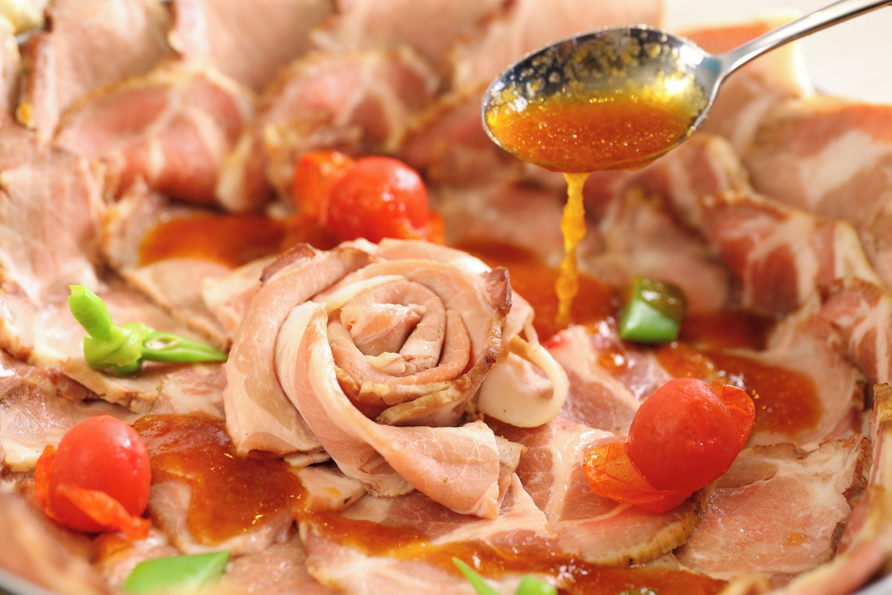A close-up of sliced meat with a sauce being poured over it.