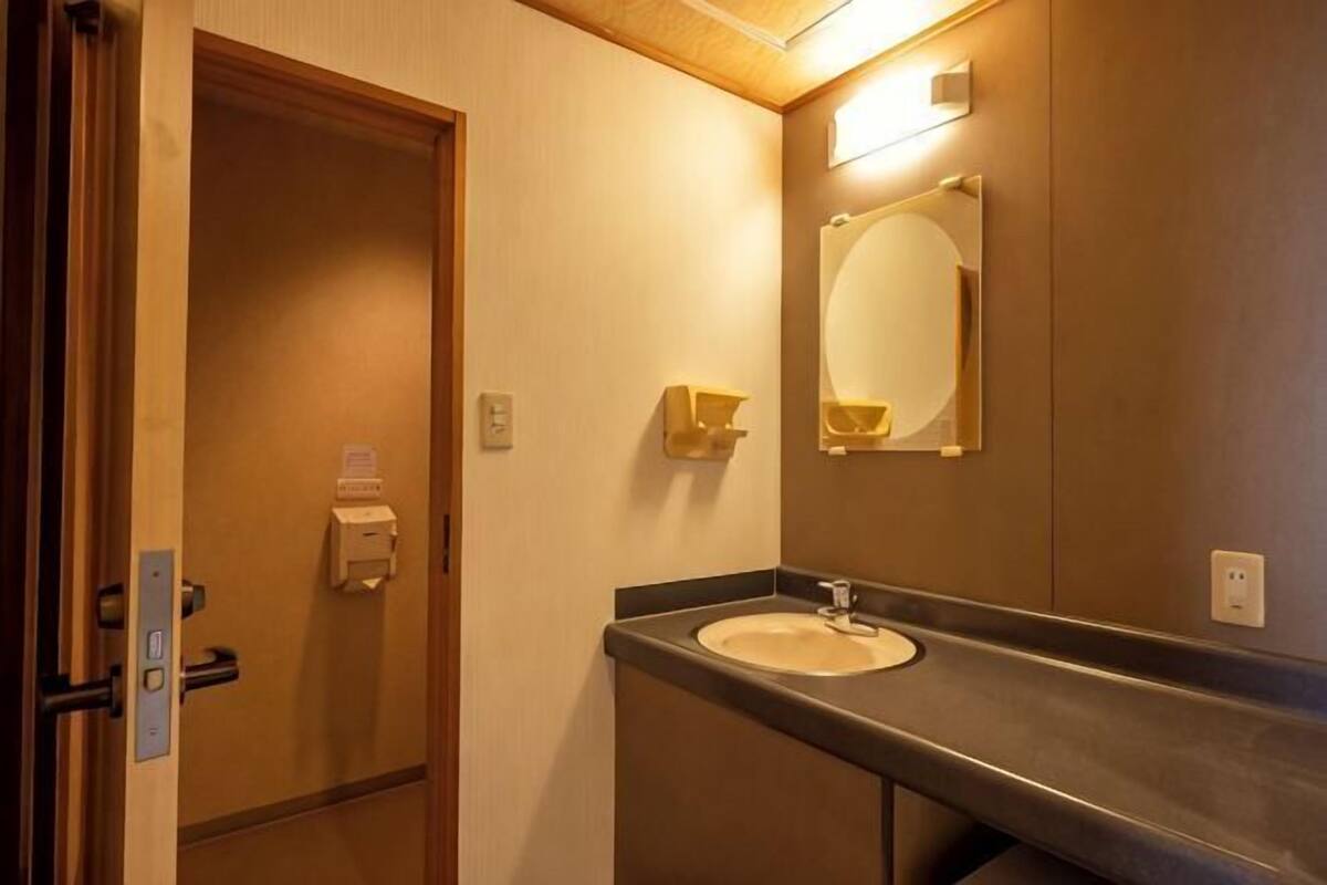 Un baño con lavamanos, espejo y puerta.