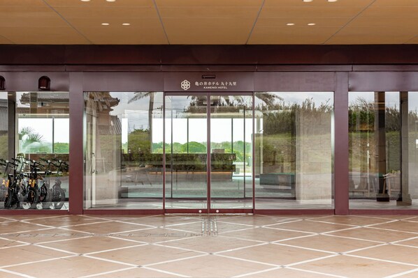 Entrada de un hotel con puerta de cristal, suelo de baldosas y un cartel sobre la puerta.